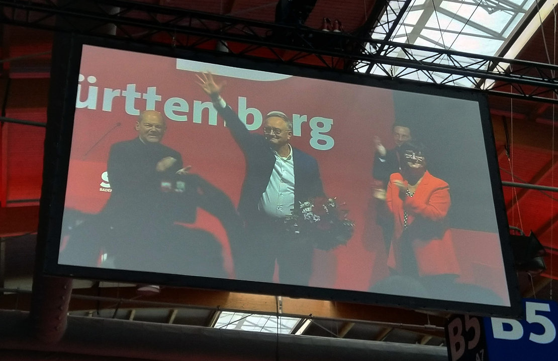 Andreas Stoch mit Blumenstrauß freut sich winkend über sein Wahlergebnis. Links und rechts von ihm applaudieren Olaf Scholz und Saskia Esken.